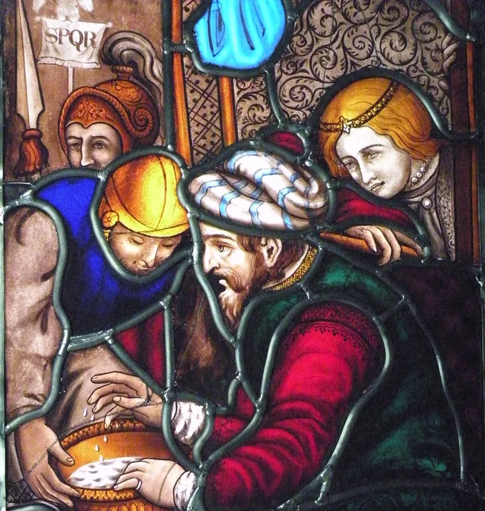 A close view of a restored stained glass panel: four figures gathered around a golden vessel.