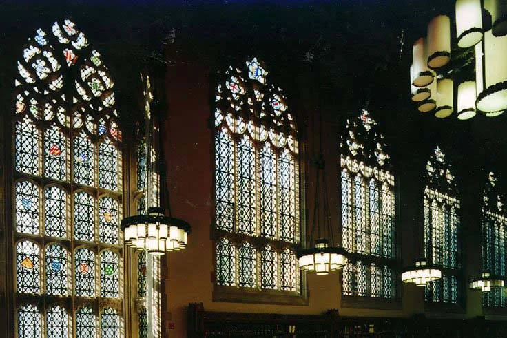 The reading room of Yale Law School, tall leaded windows down one wall under hanging lamps.
